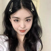 A close-up portrait of a woman with long black hair wearing silver metal star hairpins.