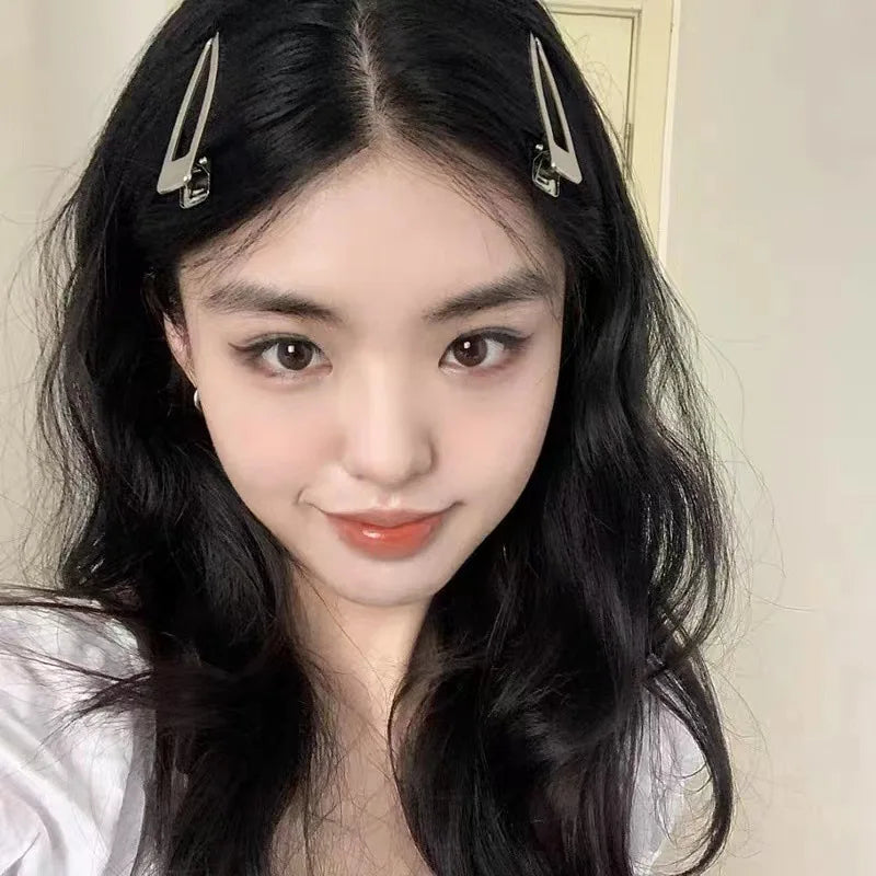 A close-up portrait of a woman with long black hair wearing silver metal star hairpins.