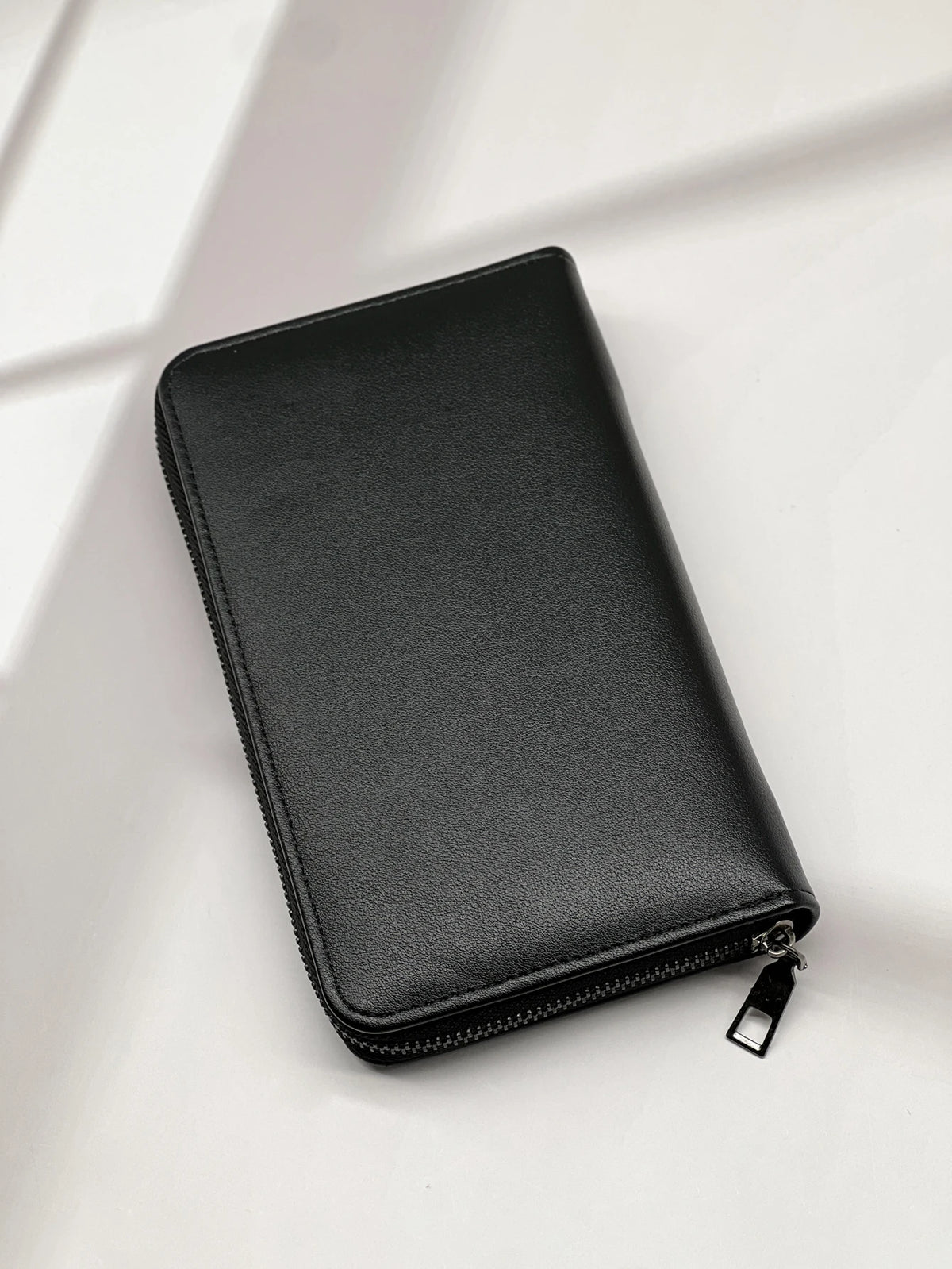 A black multi-card men's commuter wallet lying on a white surface.