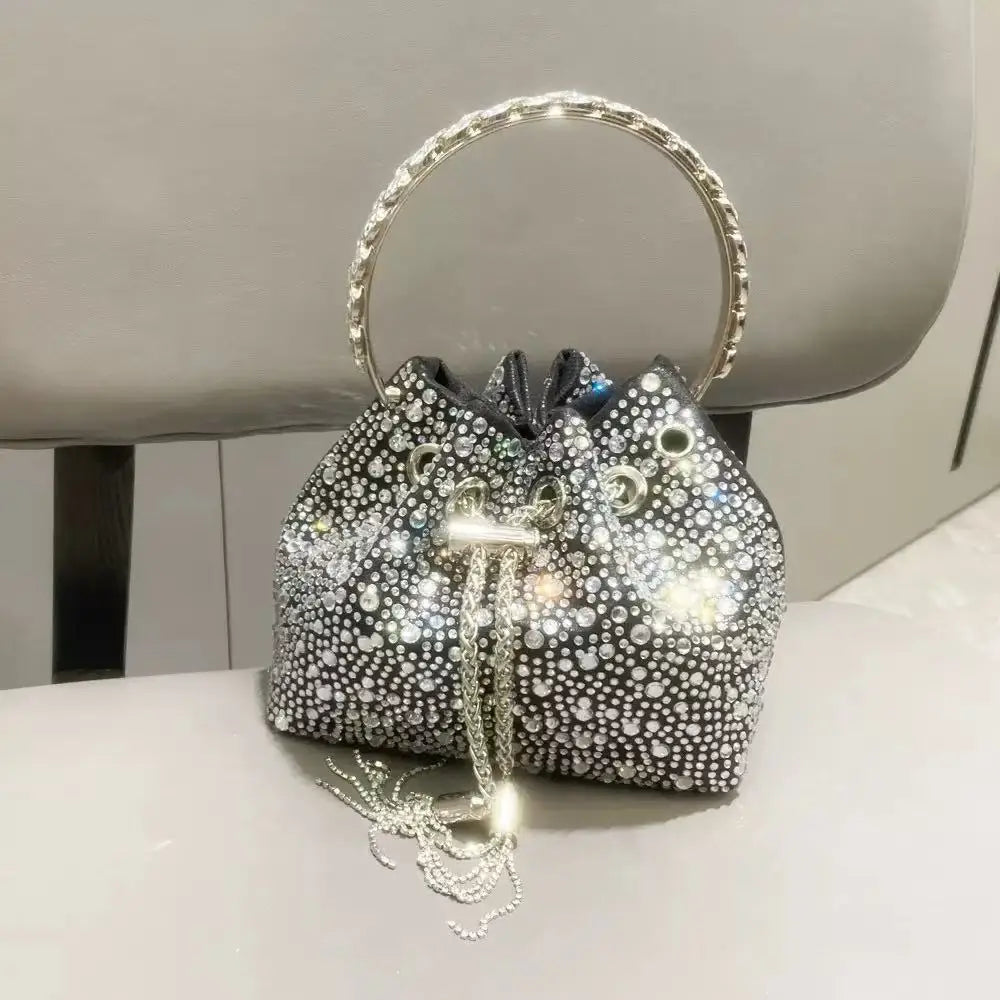 A silver chain crystal-embellished evening clutch bag resting on a white surface.