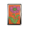 A vintage snap metal card holder featuring a pressed pink and green flower on an orange background.