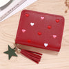 A red PU leather compact wallet with a zipper closure and heart-shaped embellishments, featuring a tassel.