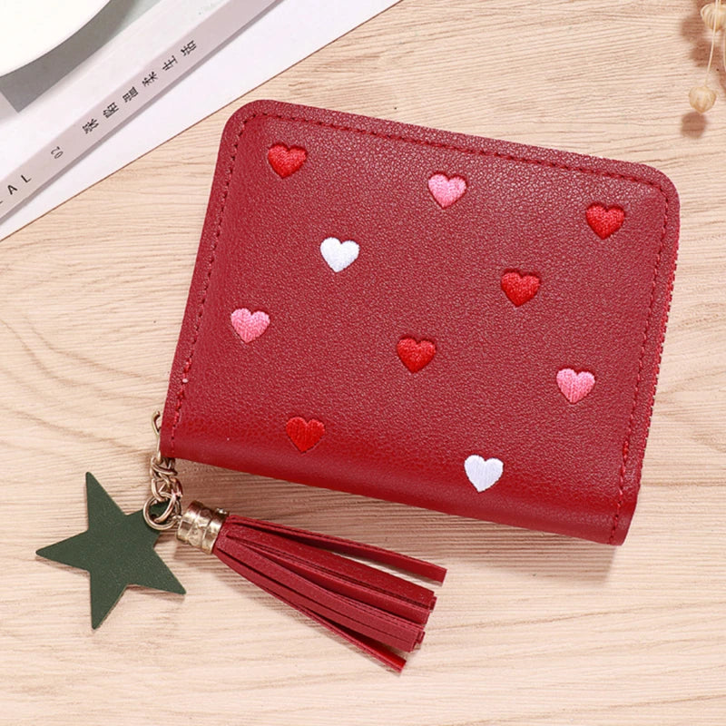 A red PU leather compact wallet with a zipper closure and heart-shaped embellishments, featuring a tassel.