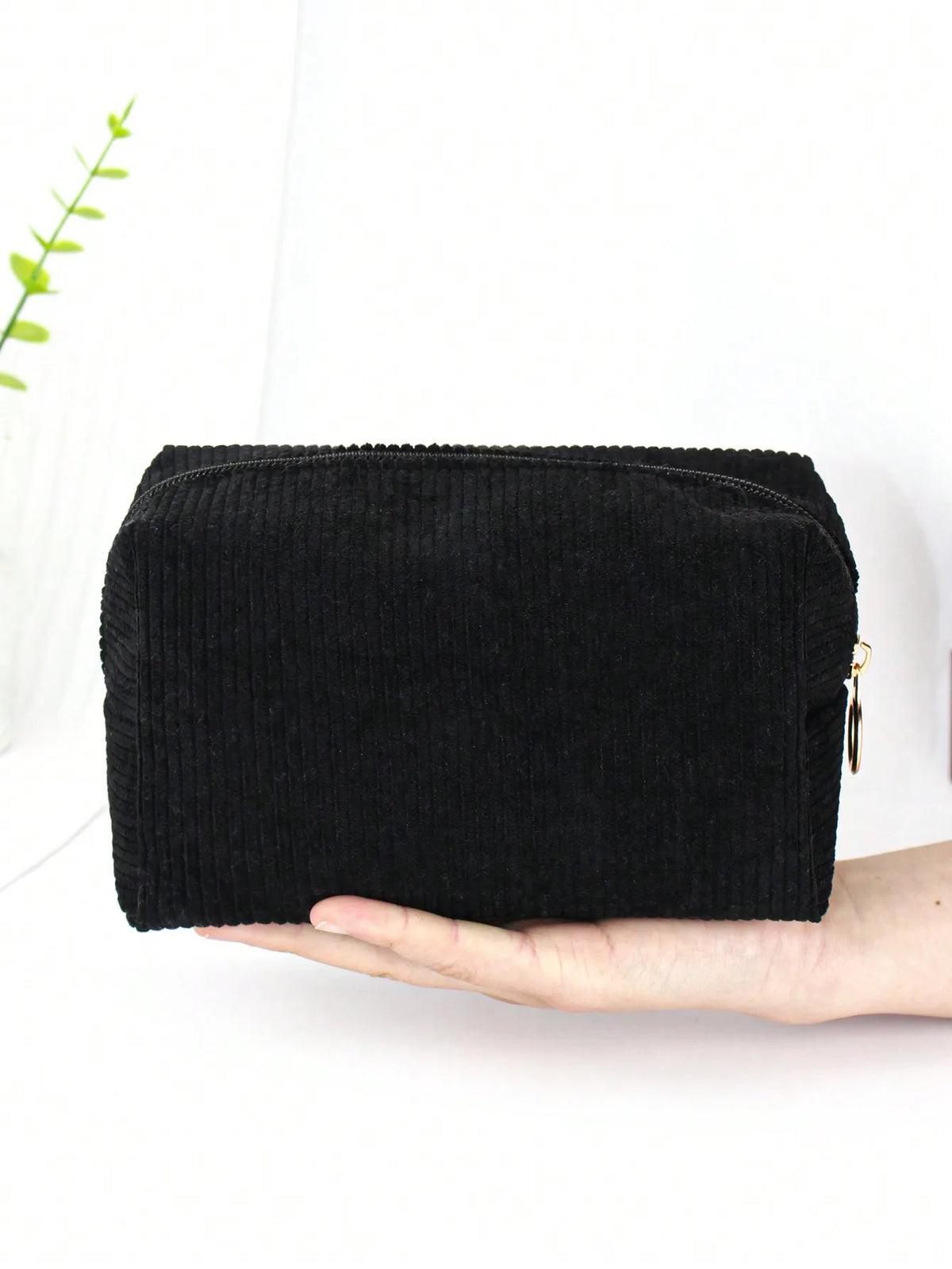 Black corduroy makeup organizer bag with an octagonal design held in a hand.