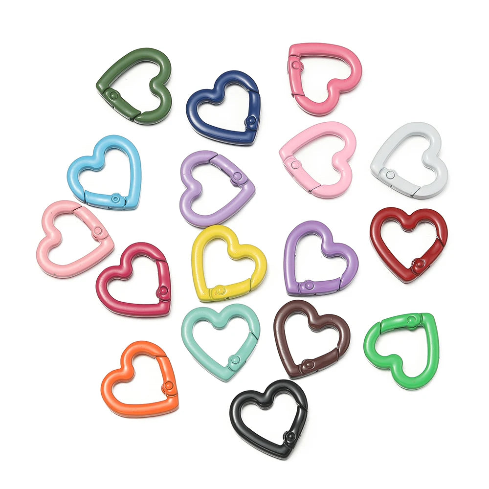 A collection of various heart-shaped metal spring clasps in different colors including green, blue, pink, purple, and silver.