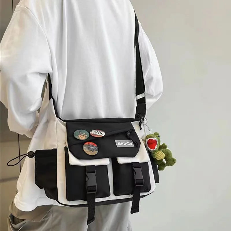 Una persona sostiene un bolso cruzado de nylon blanco y negro con un juguete de peluche verde.
