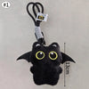 Colgante llavero de peluche de gato negro contra un fondo gris claro.