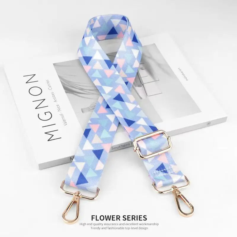 A light blue and purple patterned nylon bag strap is displayed on a white background.