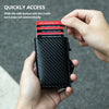 A hand holds a black carbon fiber RFID pop-up card holder with credit cards automatically popping out.