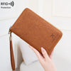 A brown leather RFID blocking passport and document holder being held by a hand.