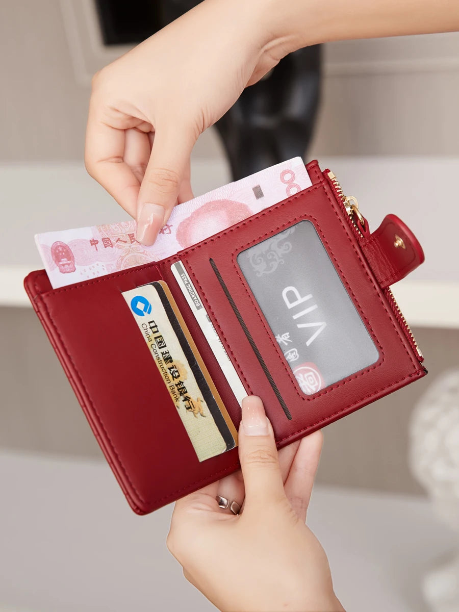 A hand is opening a maroon PU leather bifold wallet to show an ID window and credit cards.