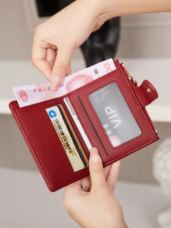 A hand is opening a maroon PU leather bifold wallet to show an ID window and credit cards.
