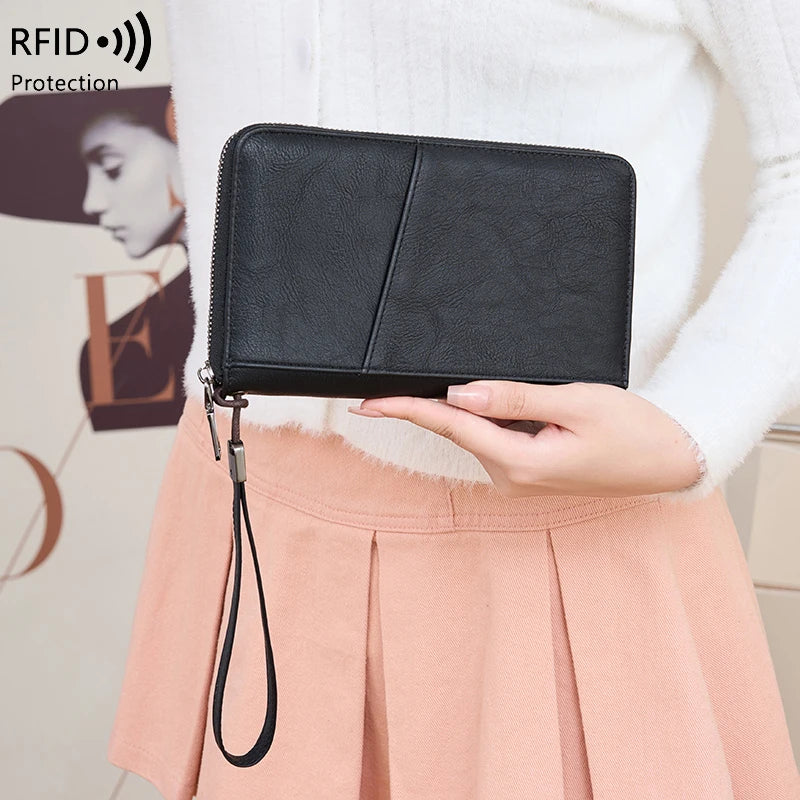 A black RFID blocking travel wallet is shown being held by a person, with a light pink skirt visible in the background.