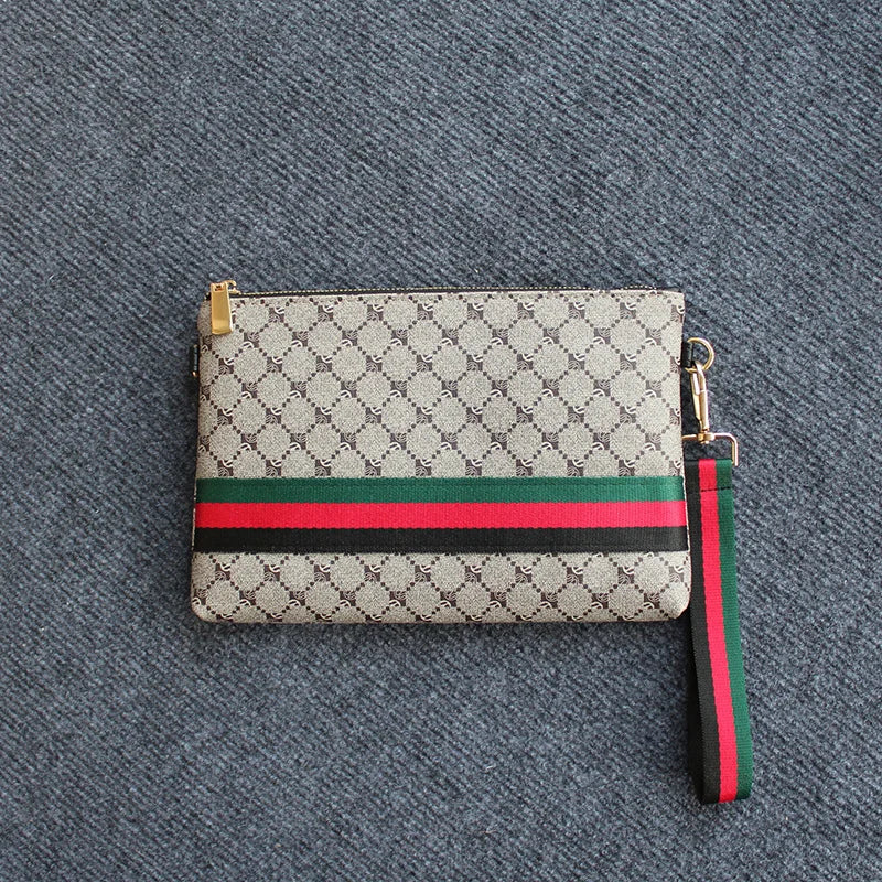 Beige und grün gemusterte Gucci-Clutch mit schwarzem Riemen auf grauem Stoff
