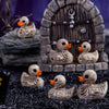 A set of gothic skull duck figurines featuring a wooden door and various sized ducks on a dark surface.