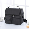 A black reusable insulated lunch bag with a handle and zippered compartments is shown on a white surface.