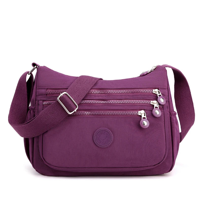 A purple waterproof nylon crossbody shoulder bag with zippered compartments and a strap.
