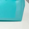 Gros plan d'un sac en gelée transparent bleu sarcelle posé sur une surface blanche.