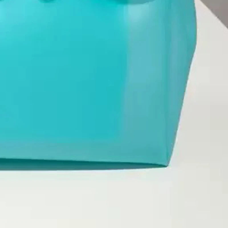 Gros plan d'un sac en gelée transparent bleu sarcelle posé sur une surface blanche.