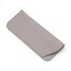 Estuche o bolsa para gafas de cuero sintético gris claro doblado y exhibido sobre un fondo blanco.