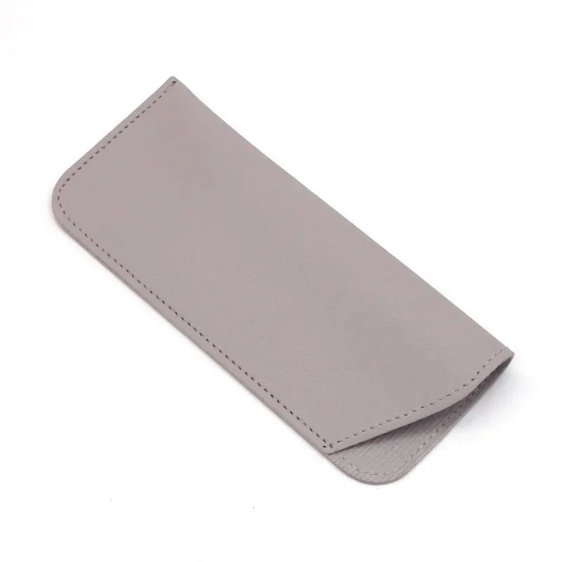 Estuche o bolsa para gafas de cuero sintético gris claro doblado y exhibido sobre un fondo blanco.