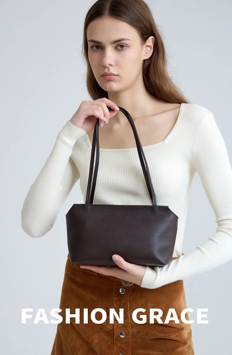 A model wearing a cream long-sleeved top holds a dark brown leather mini shoulder bag.