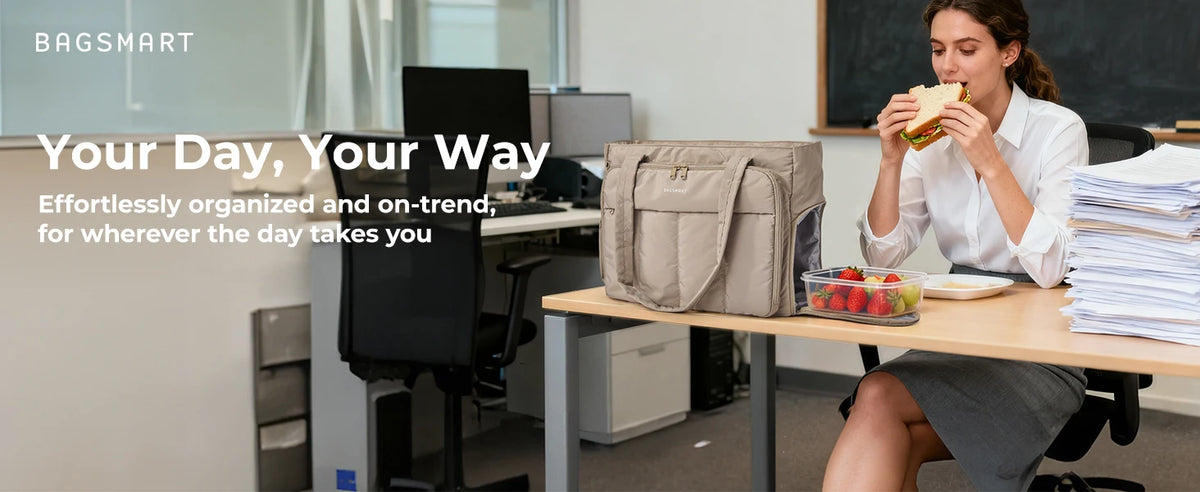 A woman is sitting at a desk working while holding food, next to an Insulated Multi-Pocket Work Tote.