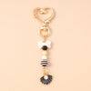 Gold-toned starfish keychain featuring pearl and black accents.