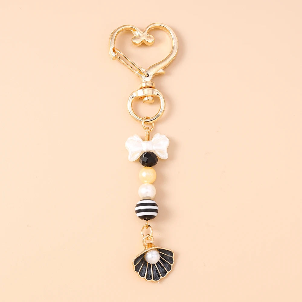 Gold-toned starfish keychain featuring pearl and black accents.