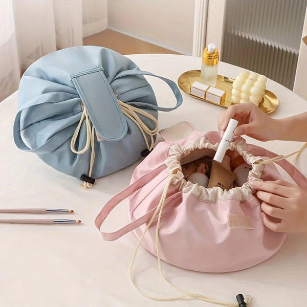 A pink instant-open flat lay makeup organizer bag is being opened, revealing makeup products and a gold bottle.