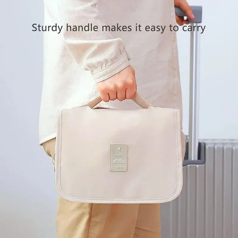 A person is carrying a light beige waterproof makeup organizer and travel pouch with a sturdy handle.