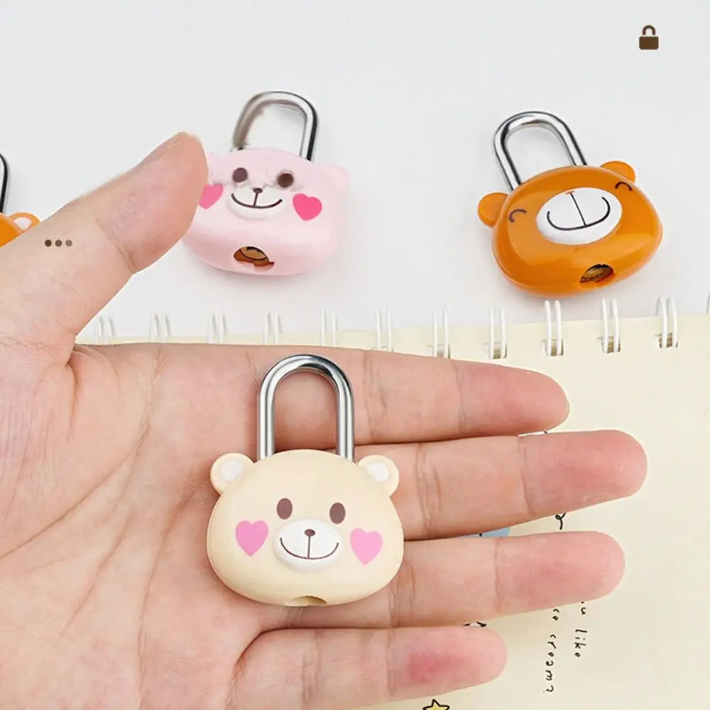 A hand holds three pink and orange cartoon combination padlocks, featuring bear faces, against a white background.