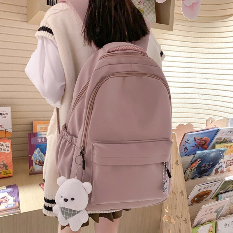 شخص يرتدي حقيبة ظهر من النايلون الوردي الفاتح للطلاب والسفر في مكان غير رسمي.