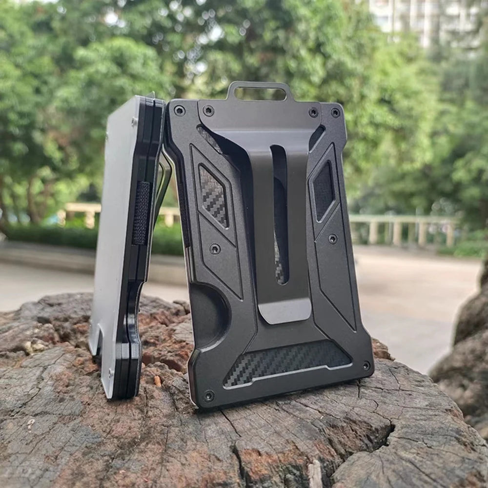 A gray slim aluminum metal ID card wallet resting on a rough, dark rock outdoors.
