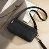 A black zippered phone pouch with a black wrist strap resting on a light wooden surface next to a notebook and a tan suit jac