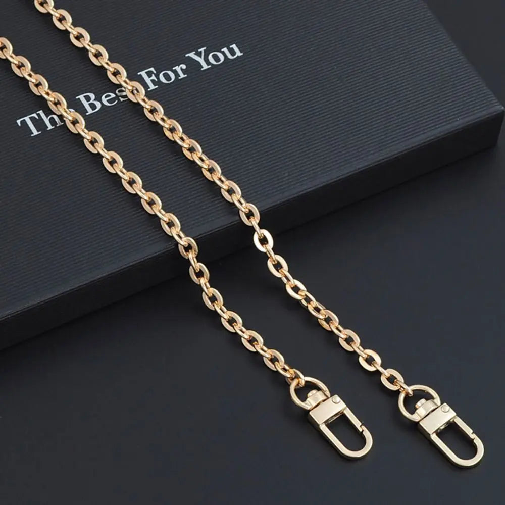 Gold metal chain strap for an adjustable crossbody bag, displayed on a dark box.