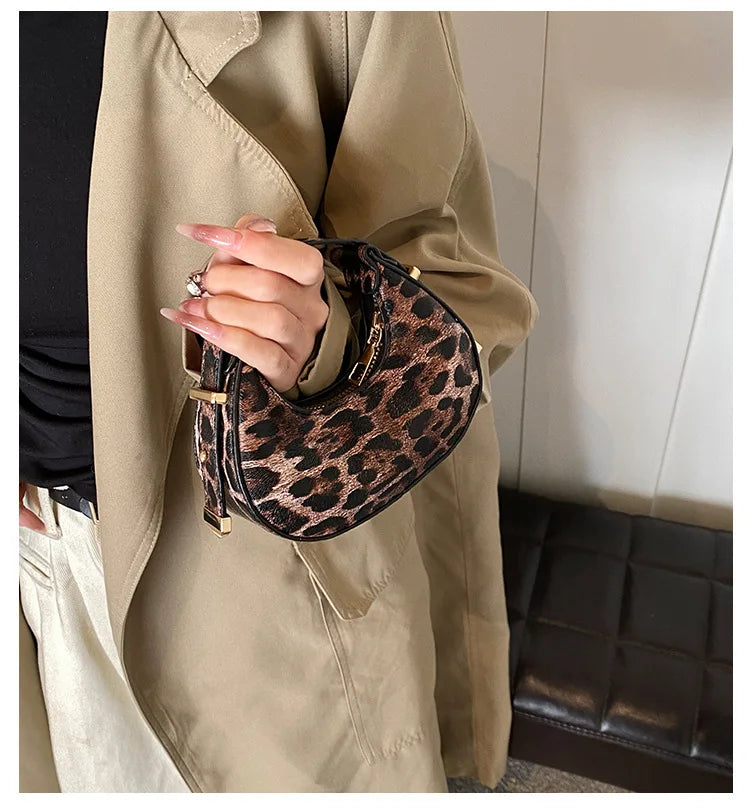 A hand holding a leopard print PU leather mini tote handbag against a beige coat.
