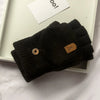 Schwarze Strickfingerless-Handschuhe mit kleinem braunem Leder-Etikett auf weißer Fläche.