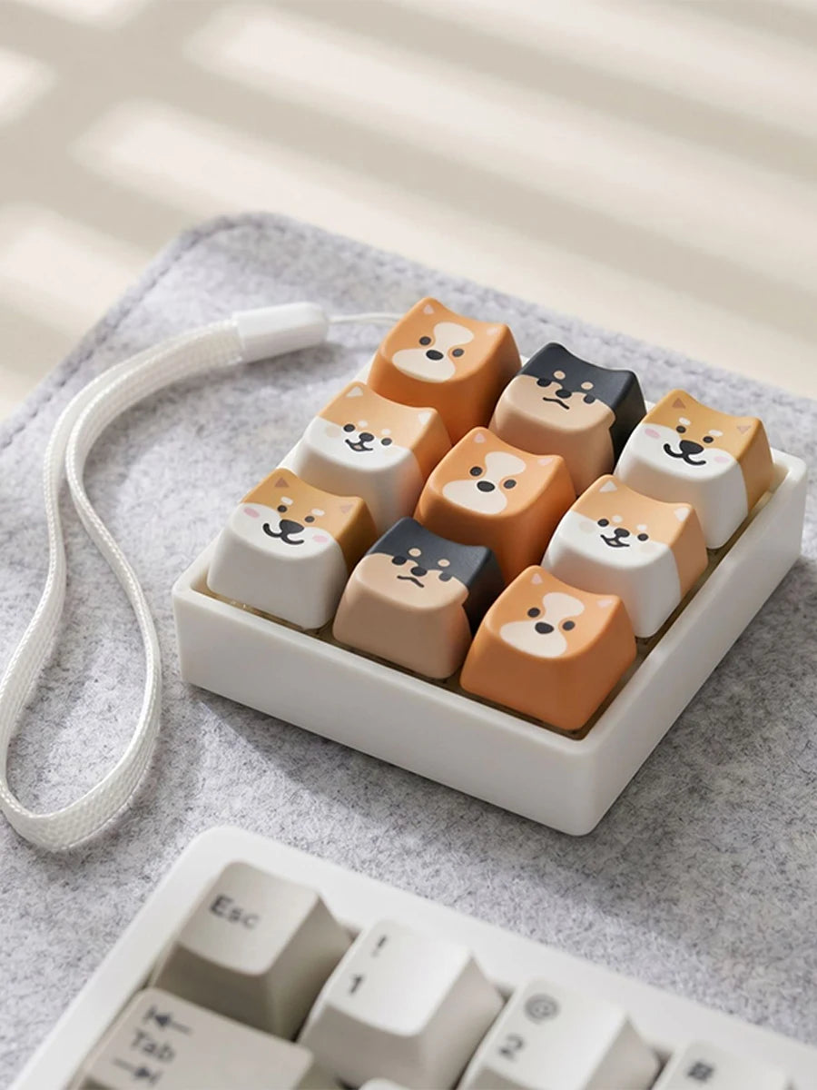 A collection of cute cat-shaped fidget toys and bag charms in various pastel and earthy tones arranged in a white dish.