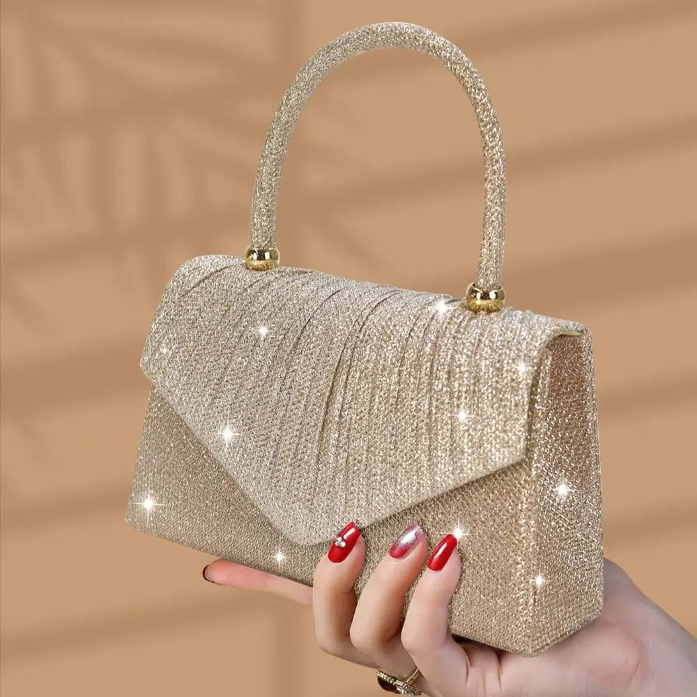 A hand holds a gold glitter sequin crossbody evening bag with a textured fabric.