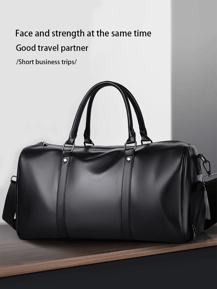 Maleta duffel de cuero negro con asas de cuero sobre una superficie de madera.