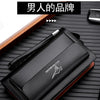 Portefeuille pochette noir homme en PU avec double fermeture éclair sur une surface en bois sombre.