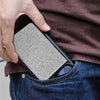 A hand holds a minimalist magnetic card holder wallet with a textured gray surface inside a denim pocket.