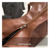 Close-up of a brown leather shoulder tote bag showing the zipper detail.