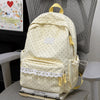 A cream-colored polka dot nylon travel backpack with yellow accents resting on a gray chair.
