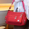 A bright red waterproof nylon crossbody tote bag being held by a person against a light background.