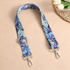 A purple and blue bohemian printed crossbody strap is displayed against a beige background.