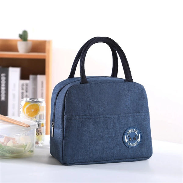 A dark blue insulated lunch bag with black handles resting on a white surface.