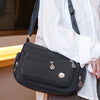A black waterproof nylon crossbody tote bag being held by a person wearing a white shirt.