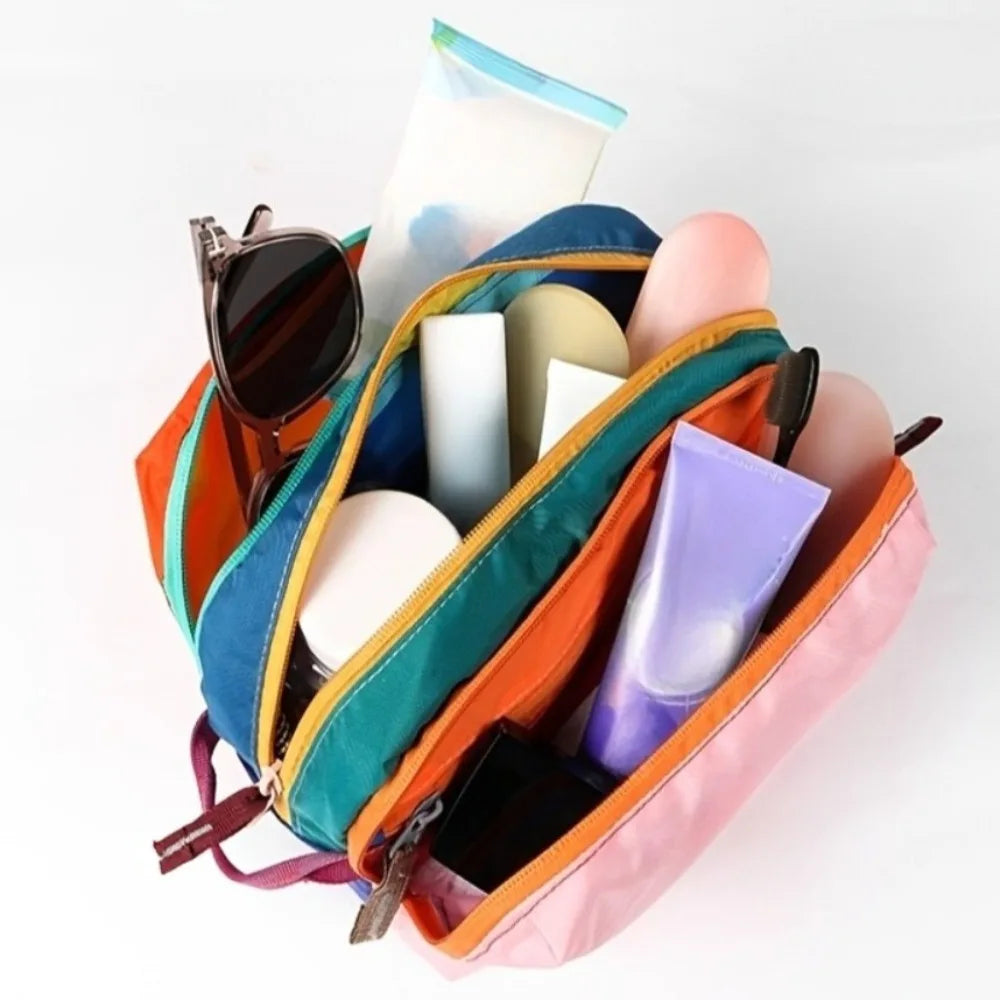 A multi-compartment travel toiletry organizer bag in orange and blue fabric holding various toiletries.